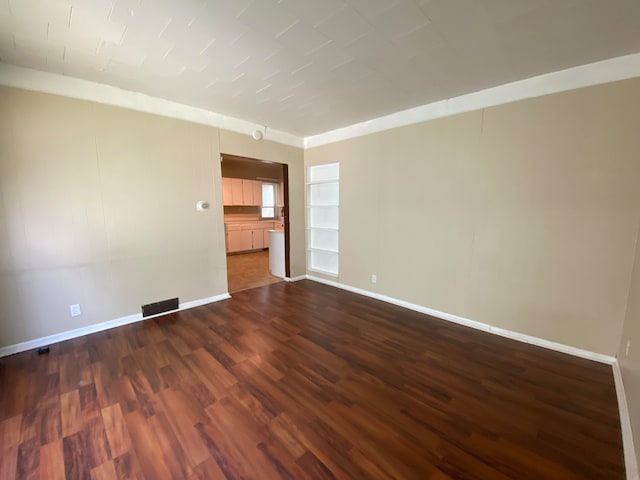 empty room with dark hardwood / wood-style floors and built in shelves