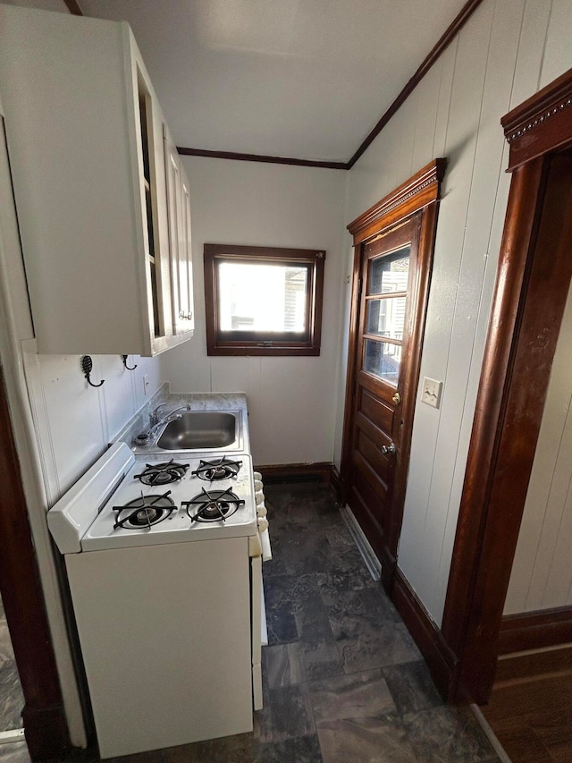 kitchen featuring wooden walls, crown molding, sink, and white range with gas cooktop