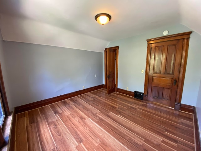 unfurnished bedroom with dark hardwood / wood-style flooring and lofted ceiling