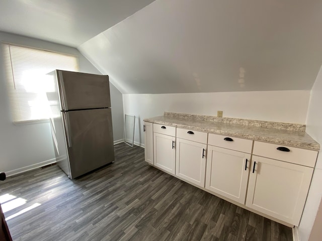 kitchen featuring lofted ceiling, dark wood-type flooring, white cabinets, stainless steel fridge, and light stone counters