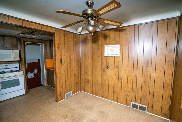 interior space with ceiling fan and wooden walls