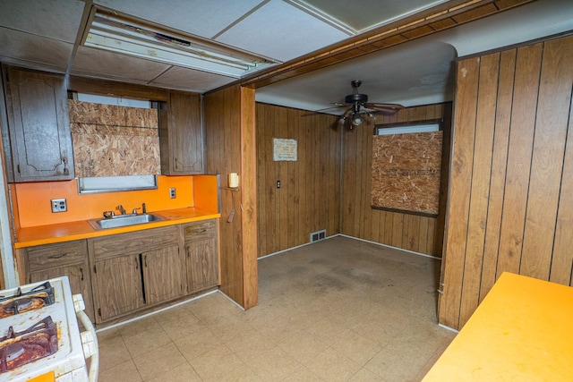 interior space featuring ceiling fan, wooden walls, and sink