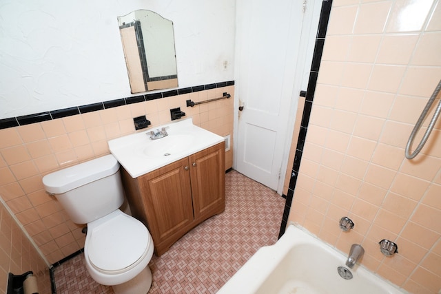 full bathroom with vanity, toilet, tile walls, and tiled shower / bath combo