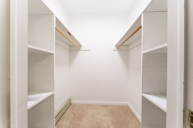 spacious closet featuring light colored carpet and a baseboard heating unit