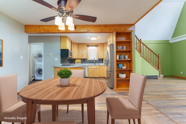 kitchen with sink, light hardwood / wood-style flooring, backsplash, stacked washer / drying machine, and appliances with stainless steel finishes