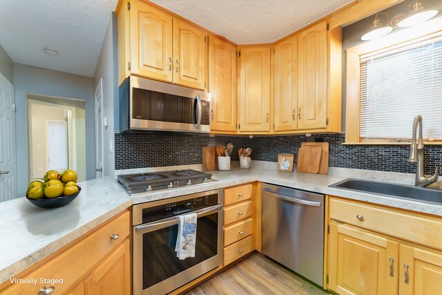 kitchen with decorative backsplash, sink, stainless steel appliances, and light hardwood / wood-style floors