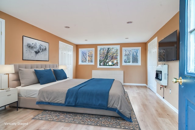 bedroom with heating unit, light hardwood / wood-style flooring, and a closet