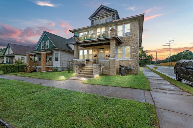 view of front of house featuring a lawn, a balcony, and covered porch