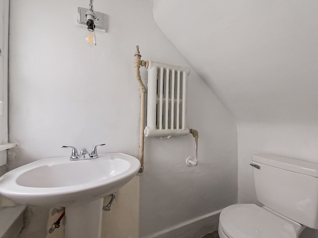 bathroom featuring toilet, lofted ceiling, sink, and radiator