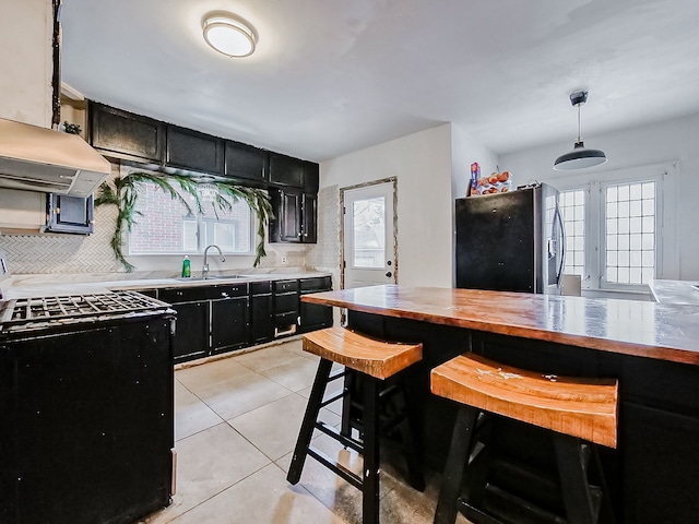 kitchen featuring sink, hanging light fixtures, black / electric stove, fridge, and a kitchen bar