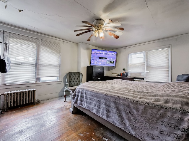 bedroom with hardwood / wood-style floors, ceiling fan, and radiator