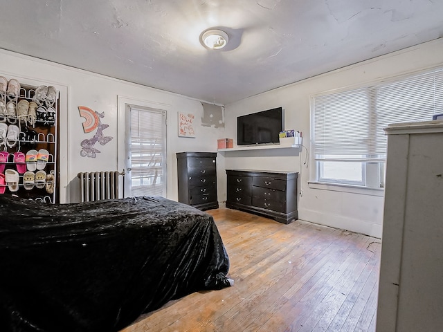 bedroom with radiator heating unit and light hardwood / wood-style floors