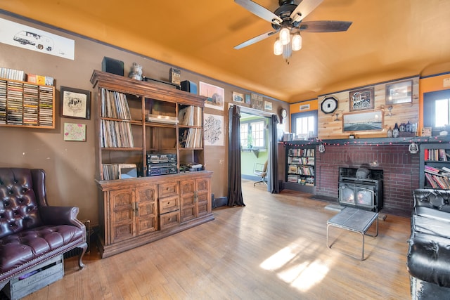 living room featuring a wood stove, ceiling fan, and light wood-type flooring