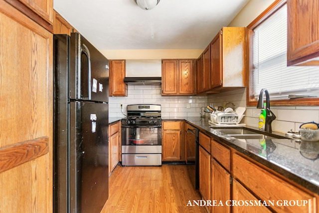 kitchen featuring backsplash, exhaust hood, sink, black appliances, and light hardwood / wood-style flooring