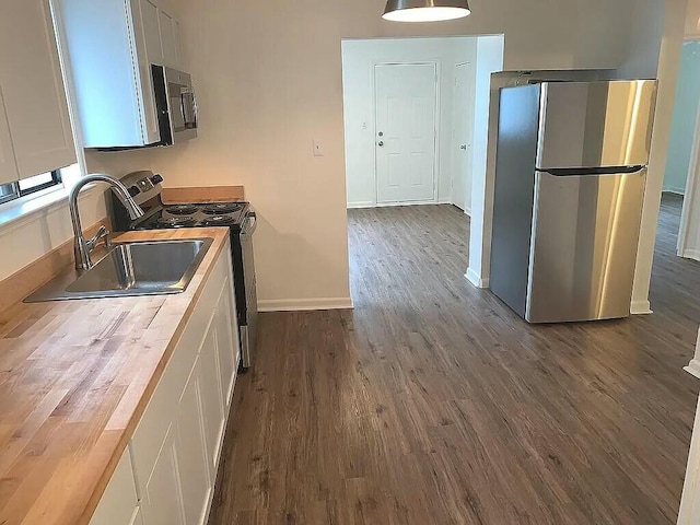 kitchen featuring white cabinetry, sink, dark wood-type flooring, butcher block countertops, and appliances with stainless steel finishes