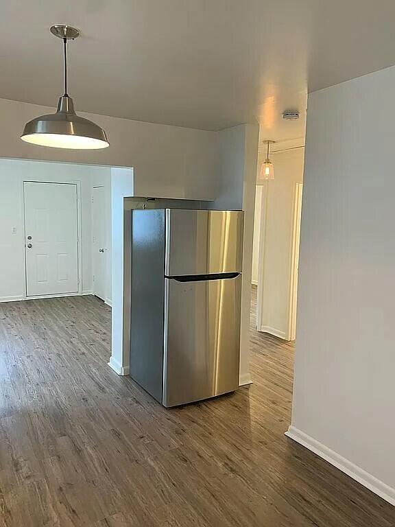 kitchen with stainless steel fridge, pendant lighting, and wood-type flooring