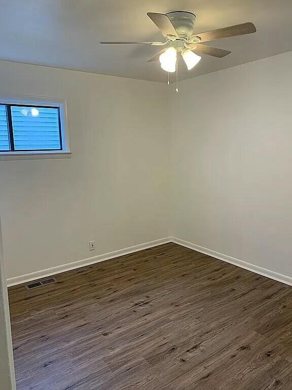 unfurnished room with ceiling fan and dark wood-type flooring