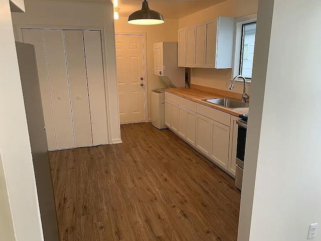 kitchen with stainless steel electric range, sink, hardwood / wood-style flooring, white cabinetry, and butcher block counters