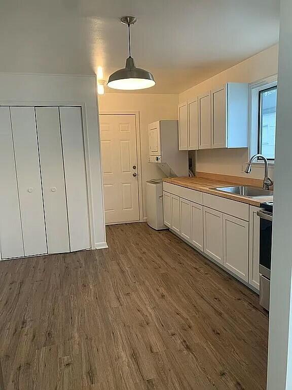 kitchen with pendant lighting, wood-type flooring, white cabinetry, and sink