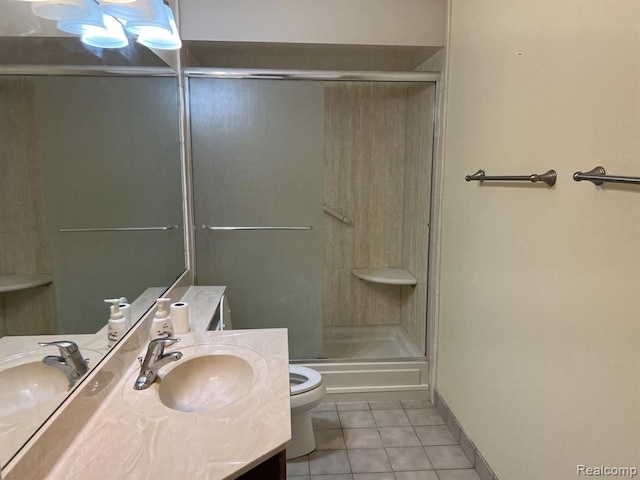 bathroom with toilet, a shower with shower door, vanity, and tile patterned floors