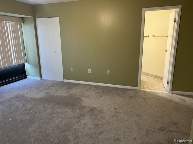 unfurnished bedroom featuring carpet floors, ensuite bath, and baseboards