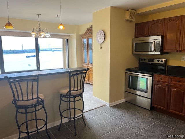 kitchen featuring a breakfast bar, a notable chandelier, dark countertops, hanging light fixtures, and appliances with stainless steel finishes