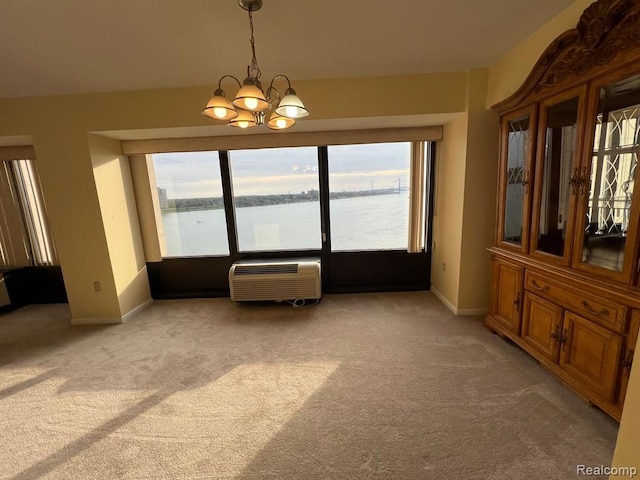 interior space with a wall mounted air conditioner, a water view, a notable chandelier, and light carpet