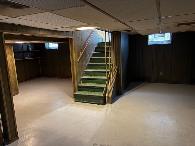 basement with wood walls and a drop ceiling