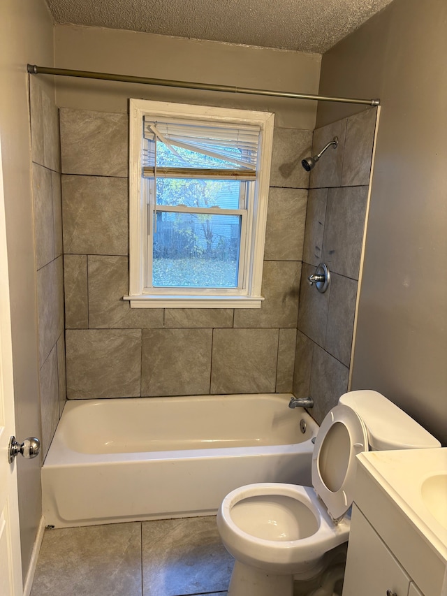 full bathroom featuring toilet, vanity, a textured ceiling, and tiled shower / bath combo