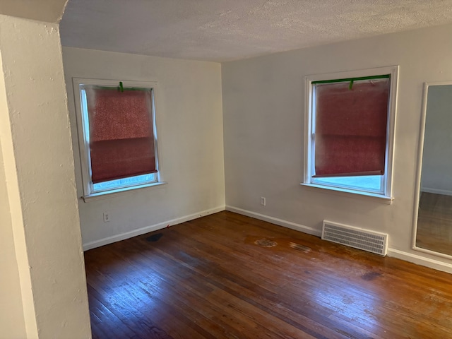 unfurnished room featuring dark hardwood / wood-style flooring and a textured ceiling