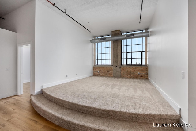 empty room featuring hardwood / wood-style floors, brick wall, and a textured ceiling