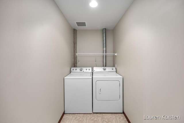 laundry area with washing machine and clothes dryer and light tile patterned floors