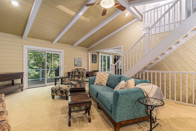 carpeted living room with vaulted ceiling with beams, ceiling fan, and wood walls