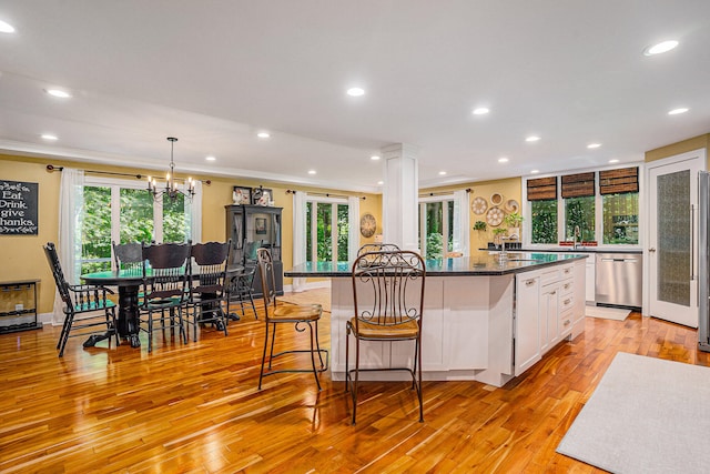 kitchen featuring white cabinets, hanging light fixtures, light hardwood / wood-style flooring, appliances with stainless steel finishes, and a healthy amount of sunlight