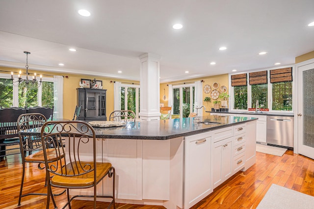 kitchen featuring sink, stainless steel dishwasher, light wood-type flooring, an island with sink, and plenty of natural light