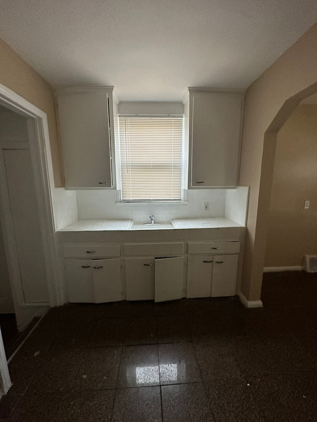 kitchen with white cabinets, a textured ceiling, backsplash, and sink