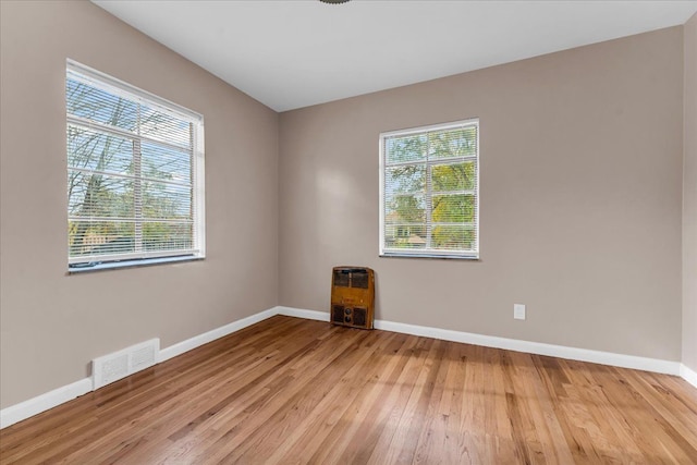 empty room with light hardwood / wood-style floors and heating unit