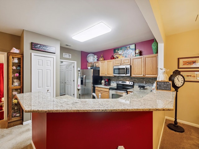 kitchen featuring backsplash, light stone countertops, light colored carpet, and appliances with stainless steel finishes