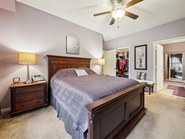 bedroom with connected bathroom, a spacious closet, ceiling fan, and light colored carpet