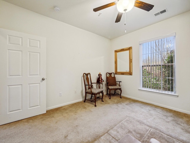 sitting room with ceiling fan and light colored carpet