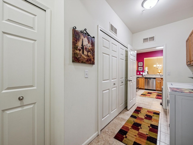 doorway to outside with a chandelier, independent washer and dryer, and light tile patterned flooring