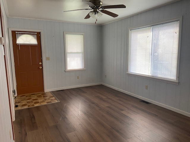 foyer with wood walls, dark hardwood / wood-style floors, ceiling fan, and ornamental molding