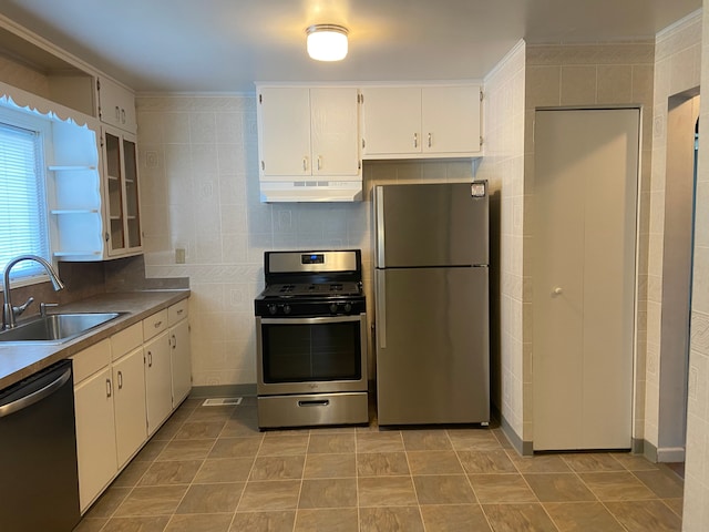 kitchen featuring white cabinets, sink, stainless steel appliances, and tile walls