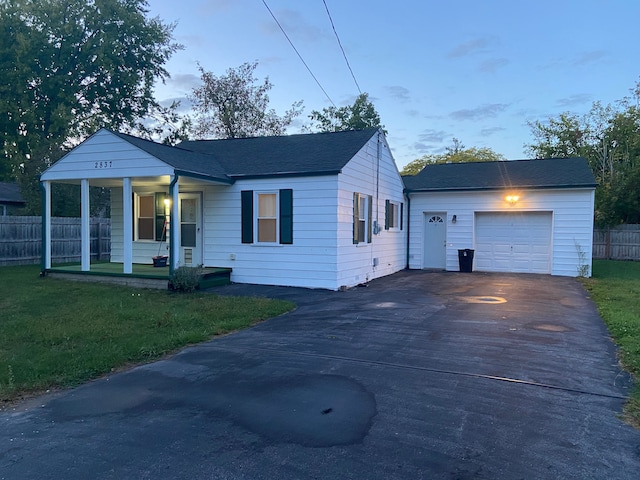 bungalow-style home with a yard, a porch, and a garage