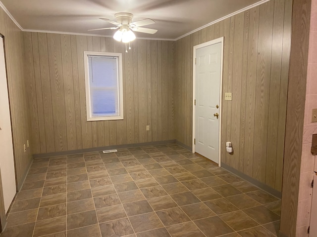 unfurnished room with wood walls, crown molding, and ceiling fan