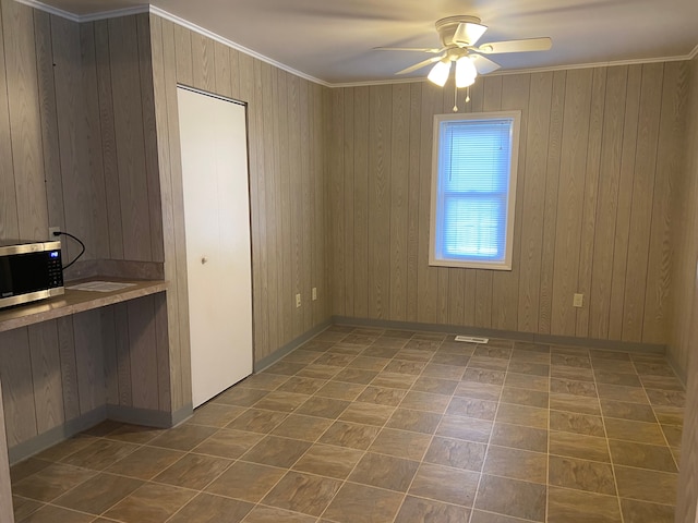 spare room with wood walls, ceiling fan, and ornamental molding