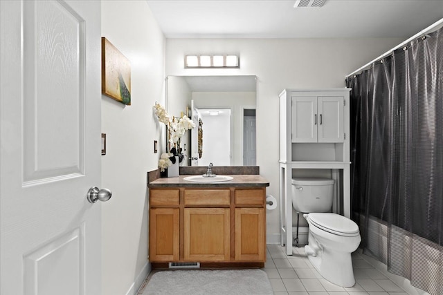 bathroom with toilet, vanity, and tile patterned floors