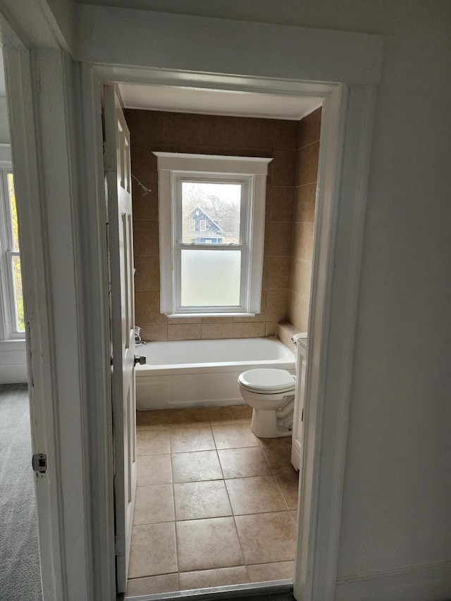 bathroom with a bath, toilet, plenty of natural light, and tile patterned floors