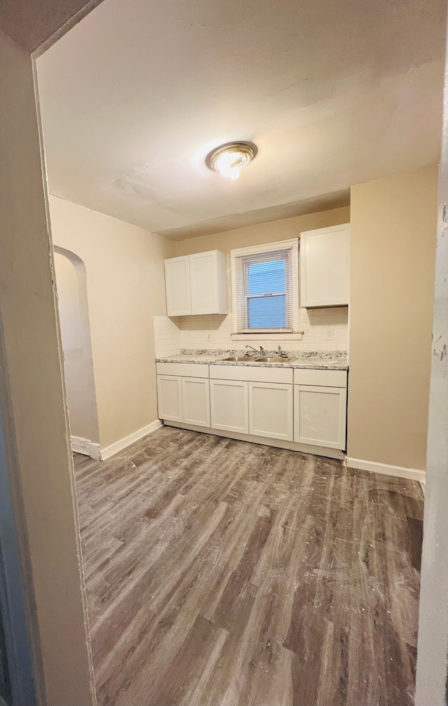 kitchen featuring light stone countertops, hardwood / wood-style flooring, and white cabinetry