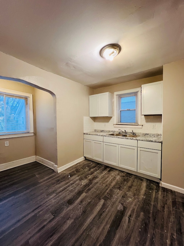 kitchen featuring dark hardwood / wood-style flooring, backsplash, light stone counters, sink, and white cabinetry